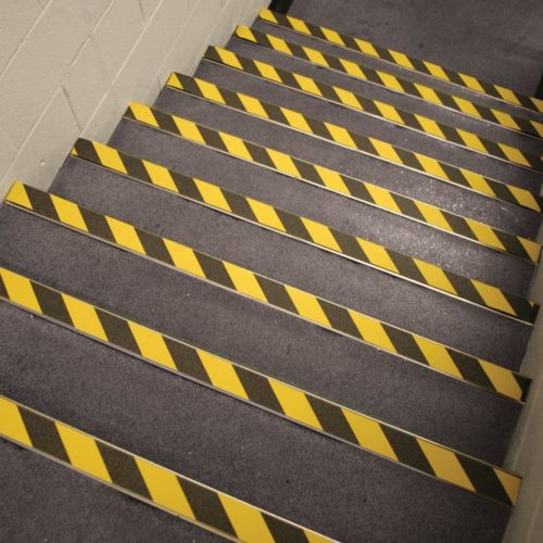 trwała taśma antypoślizgowa Gripfoot w ostrzegawczym kolorze czarno żółtym naklejona na schody wcześniej wyłożone nakładkami na schody COBAGRiP